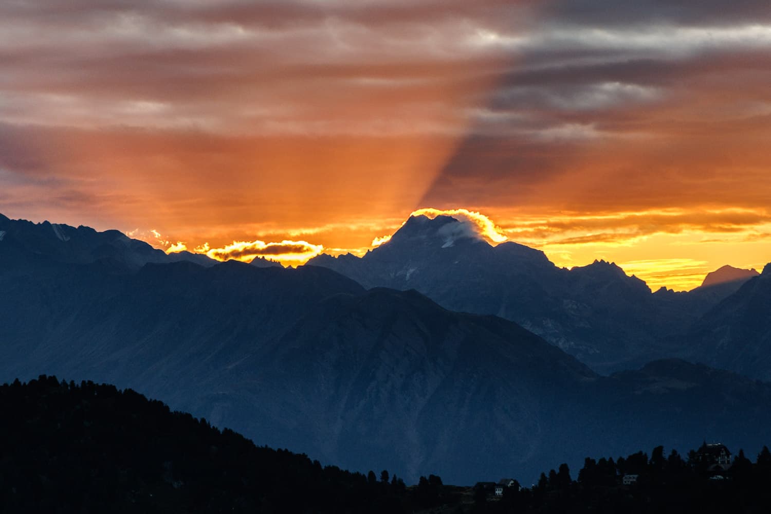 Sonnenstrahlen durchbrechen den Morgenhimmel über den Bergen